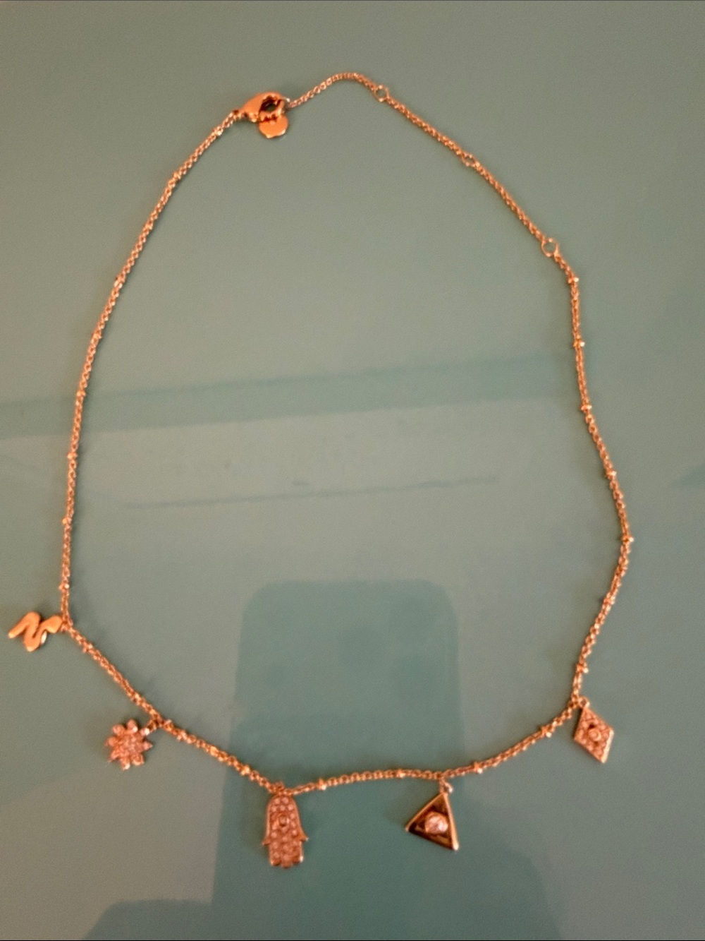 Stella & Dot rose gold charm necklace with Hamsa and geometric pendants